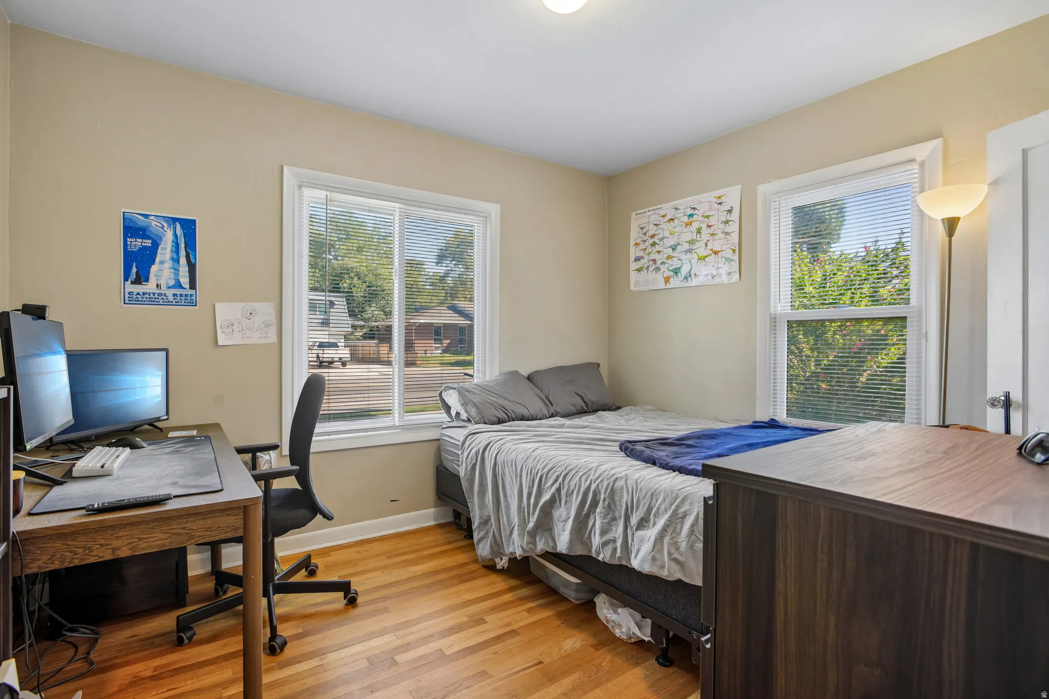 Hardwood flooring, two windows with blinds, light-colored walls, and a ceiling-mounted light fixture
