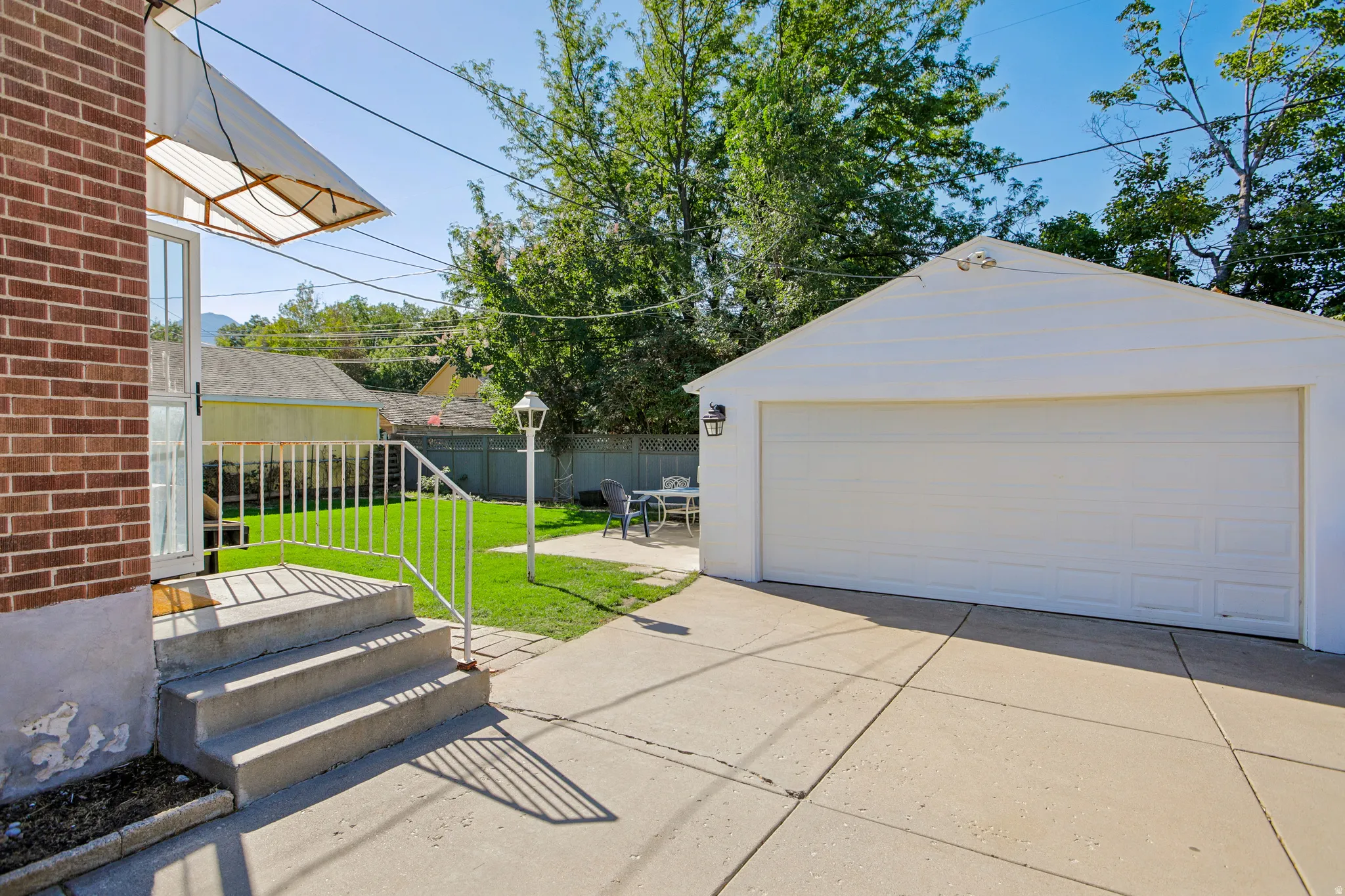 Expansive concrete driveway and patio with detached single-car garage featuring a white overhead door