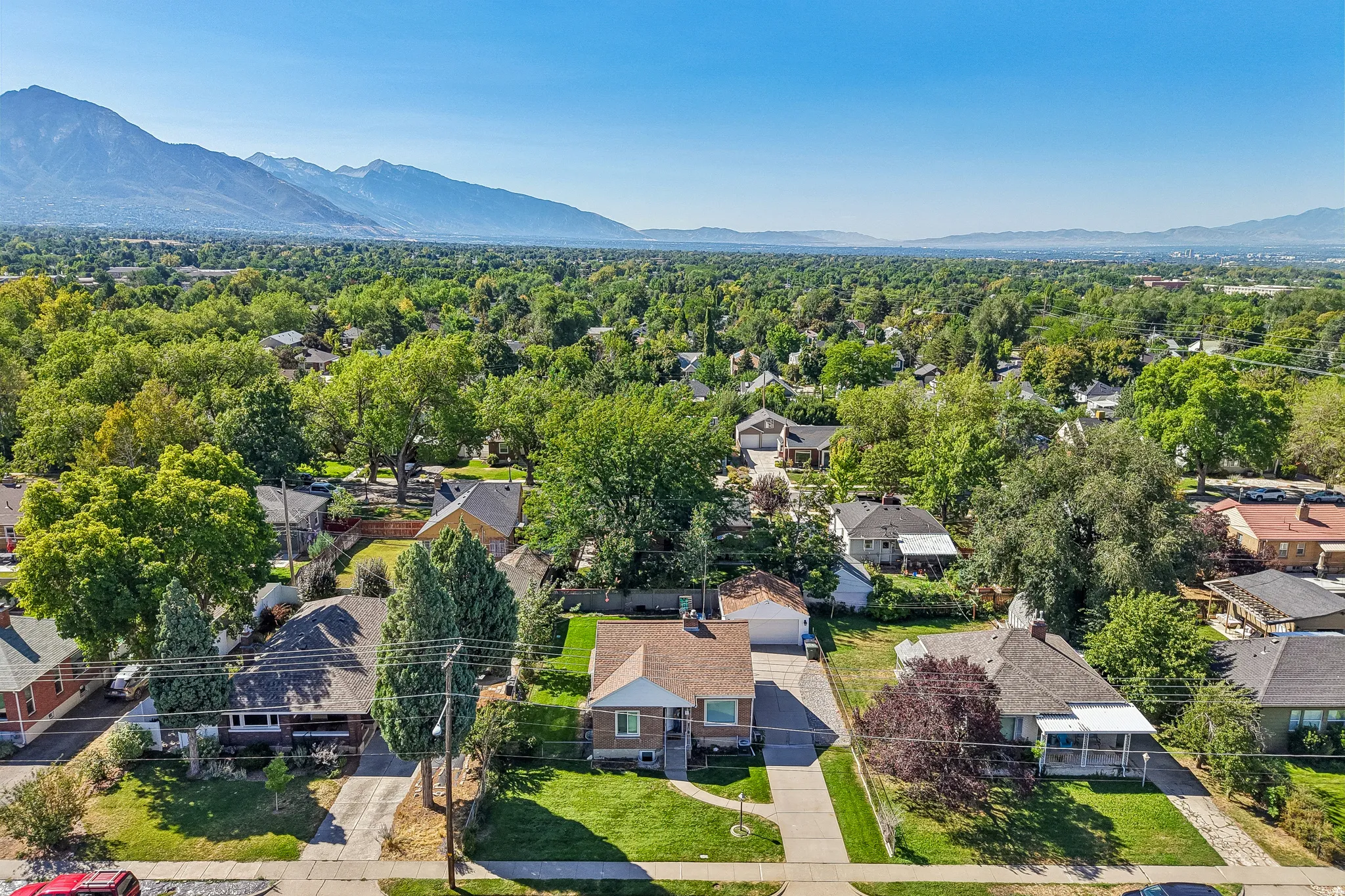 Expansive neighborhood setting with established landscaping, paved streets, and a clear mountain backdrop