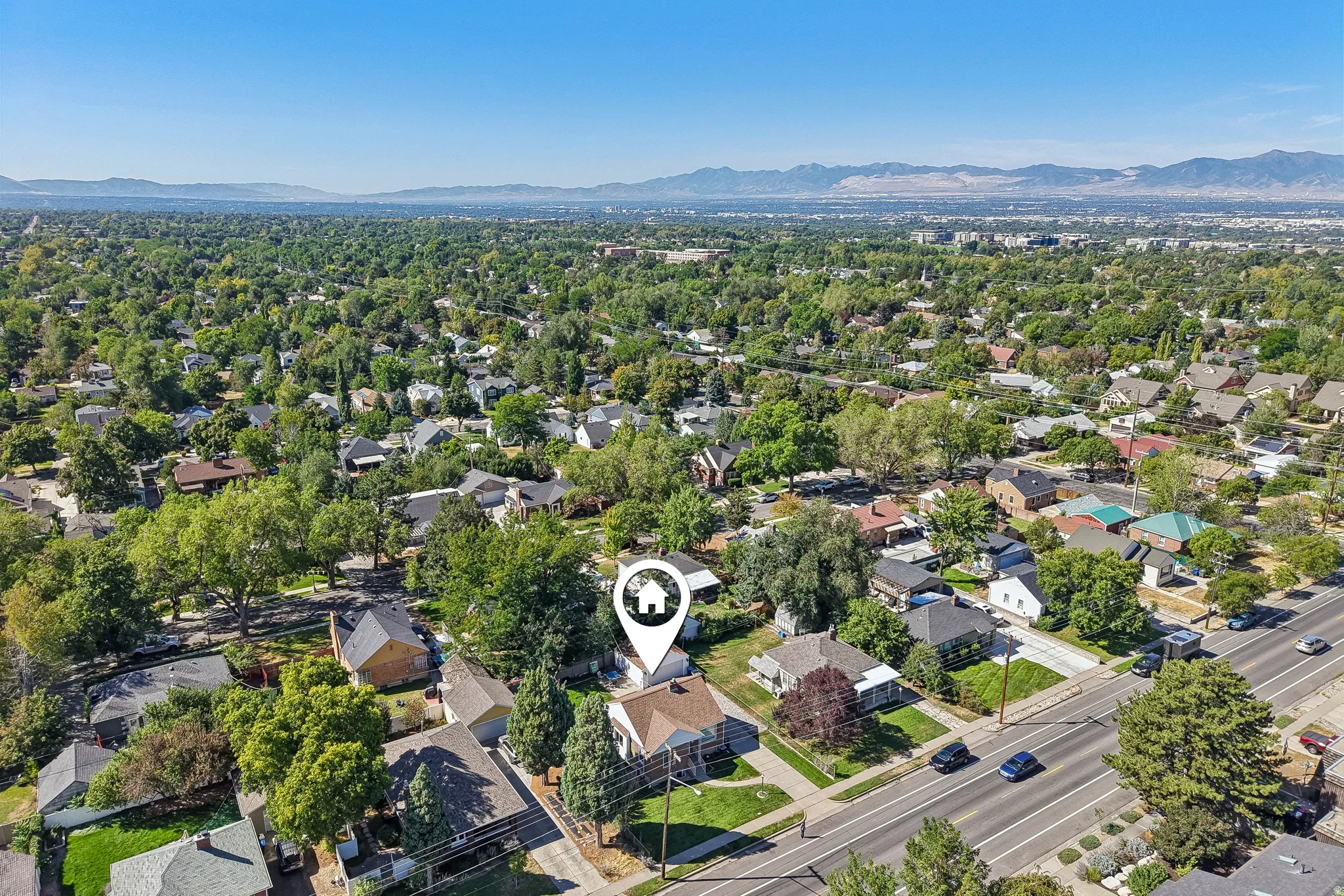 Residential property situated on a tree-lined street, featuring a mountainous backdrop and proximity to a multi-lane road
