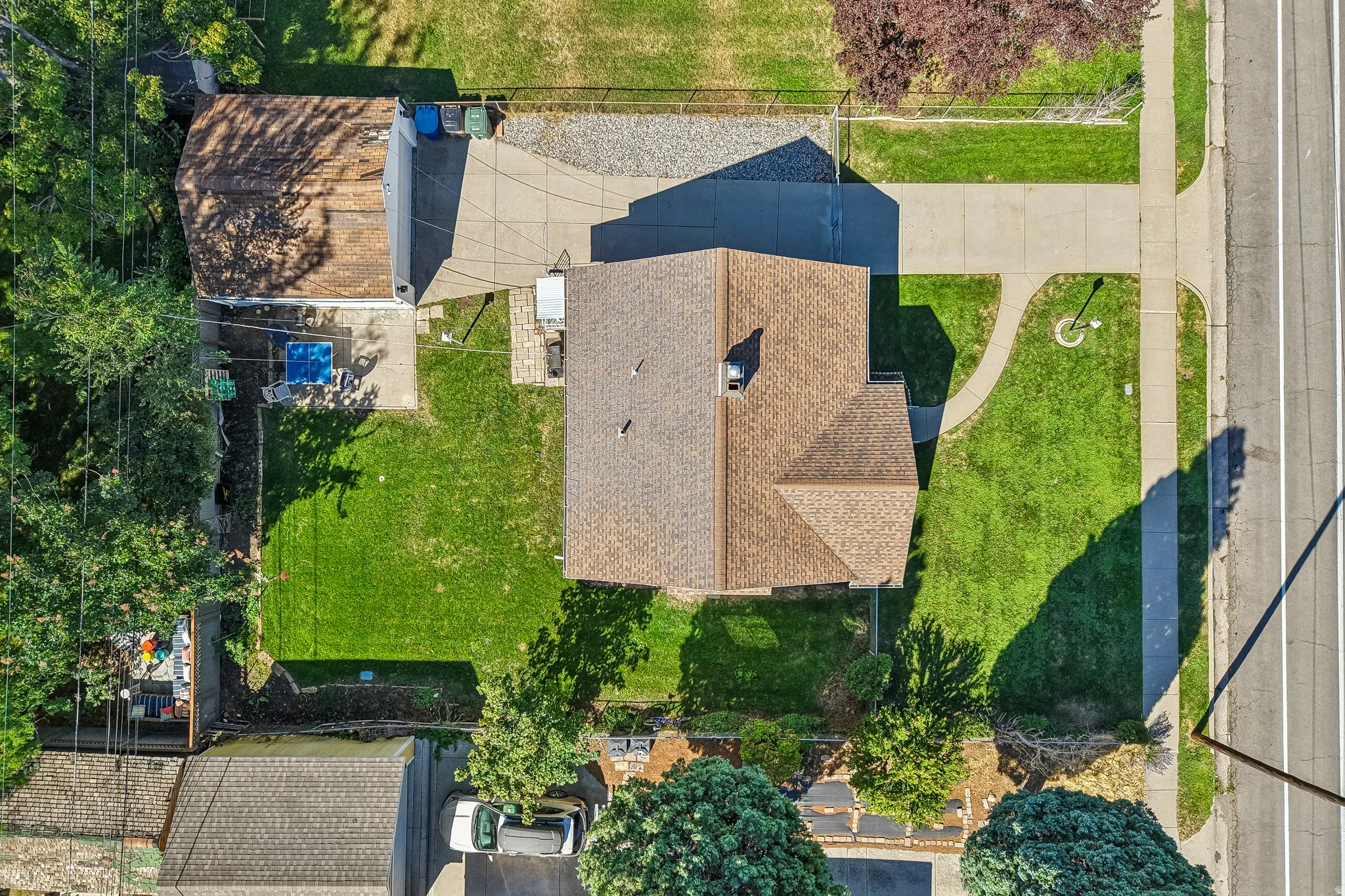 Property featuring a shingle roof, paved driveway, and established lawn