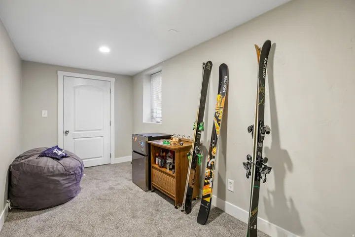 Recessed lighting illuminates a space featuring light gray walls, gray carpeting, a white door, and a horizontal window