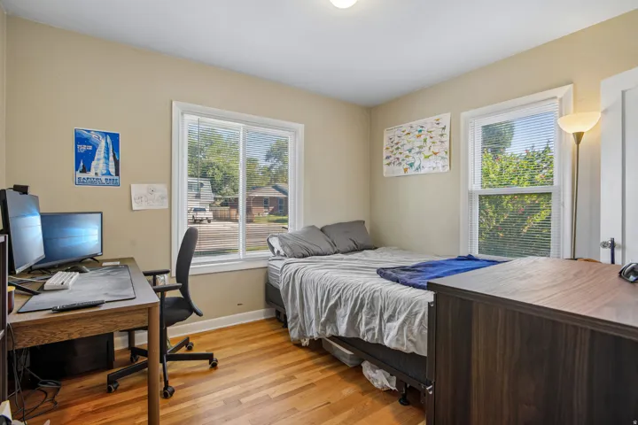 Hardwood flooring, two windows with blinds, light-colored walls, and a ceiling-mounted light fixture
