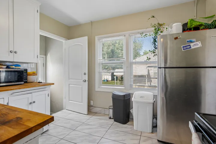 White cabinetry with chrome hardware, wood-finish countertops, and large format floor tiles