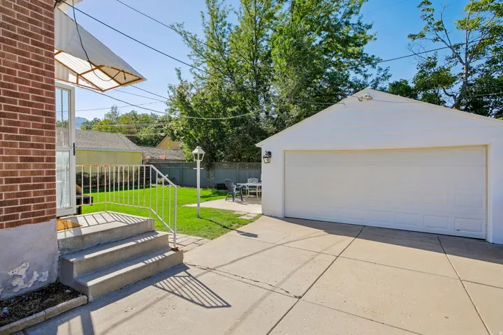 Expansive concrete driveway and patio with detached single-car garage featuring a white overhead door