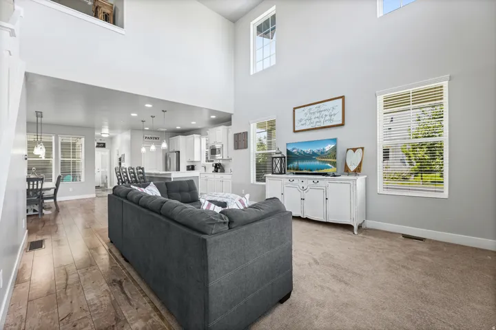 Great Room with high ceilings, multiple windows, carpet flooring, and a clear line of sight to the kitchen