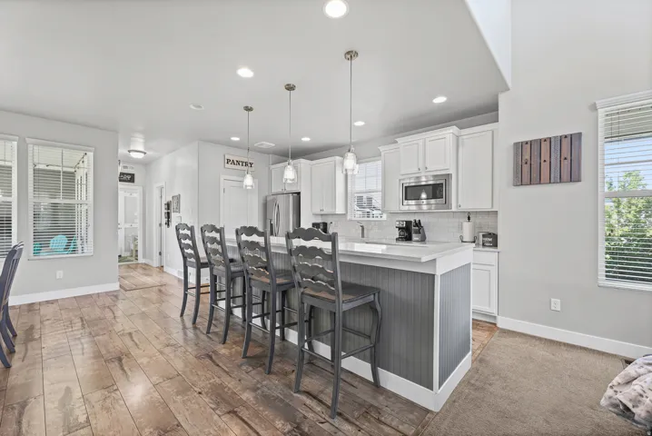 Kitchen featuring white cabinetry, stainless steel appliances, quartz countertops, and an island with bar seating.