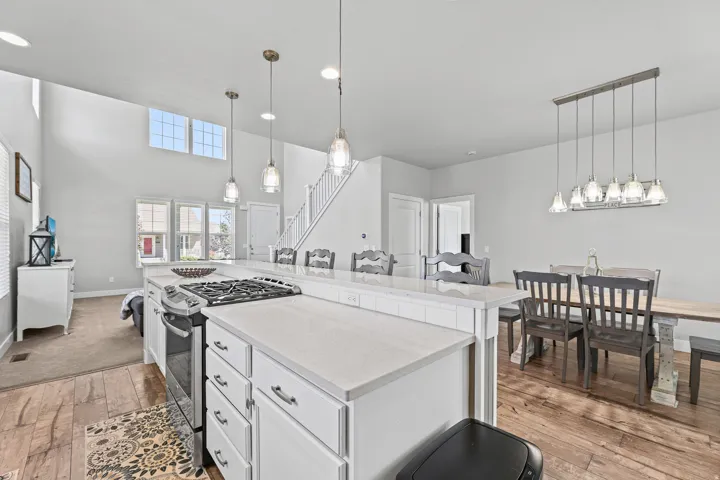 Open-concept kitchen and dining area featuring a large island with gas cooktop, white cabinetry, and quartz countertops.
