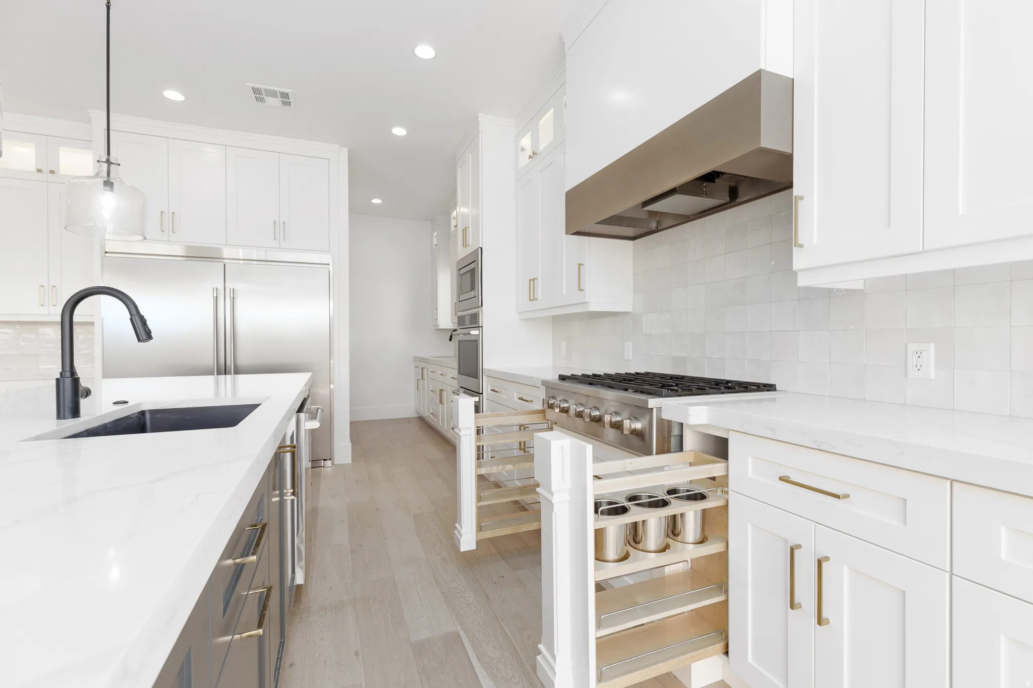 Gourmet kitchen featuring white shaker cabinetry, stainless steel appliances, a gas range with a professional hood, a built-in oven, and light wood-finish flooring
