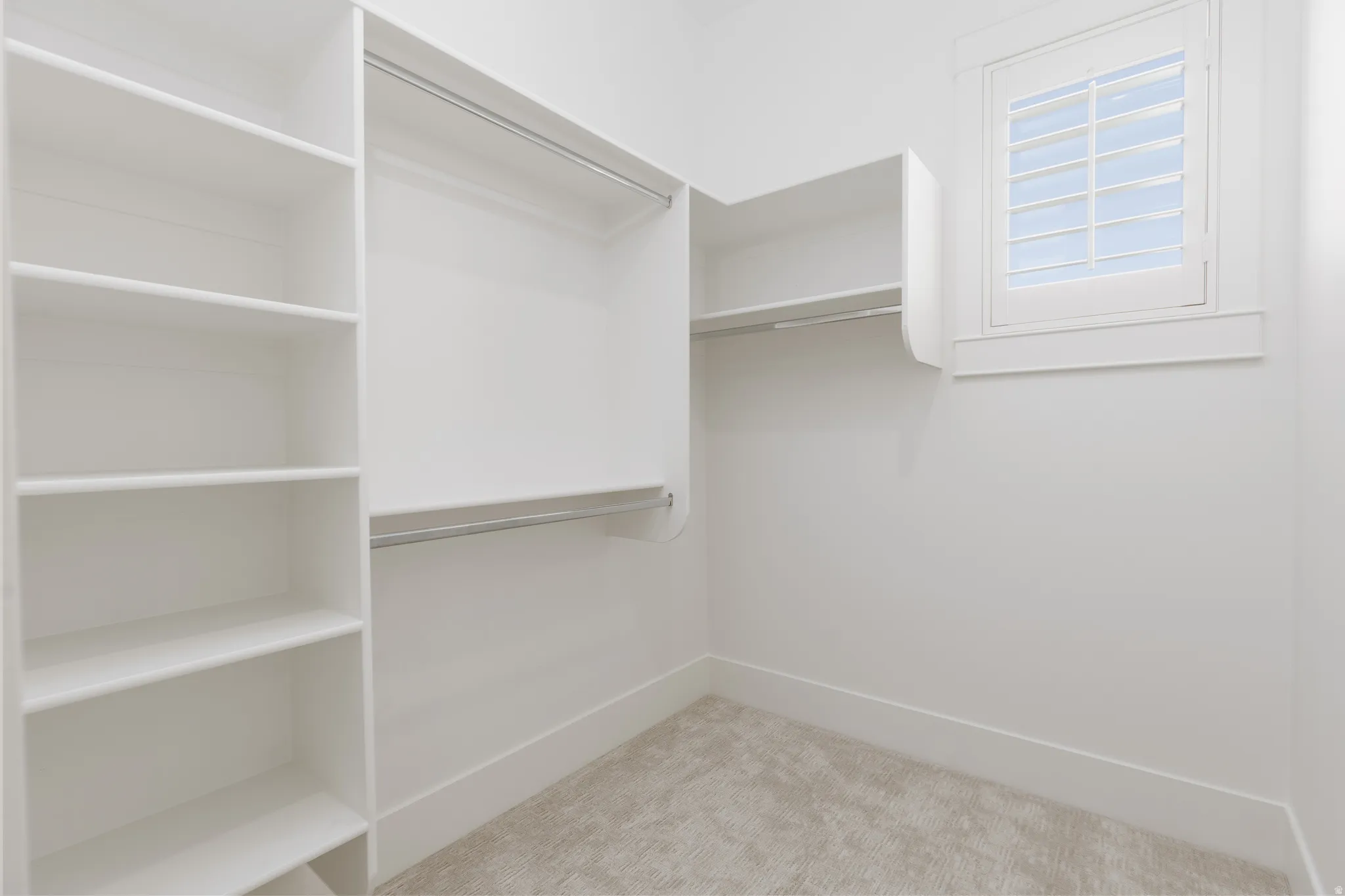 Built-in shelving, hanging rods, and a window with plantation shutters