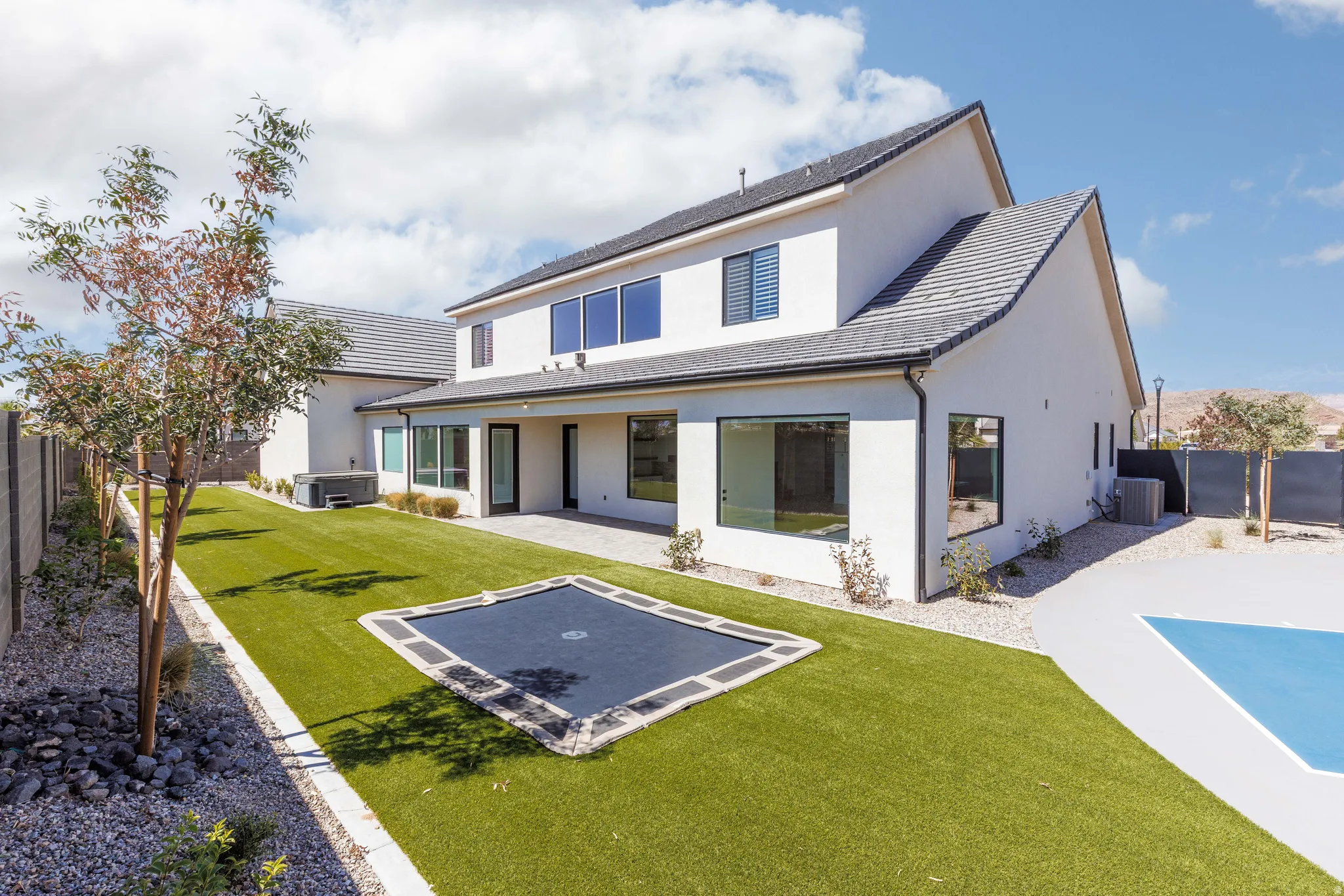 Expansive backyard featuring a manicured lawn, dedicated patio space, and mature trees