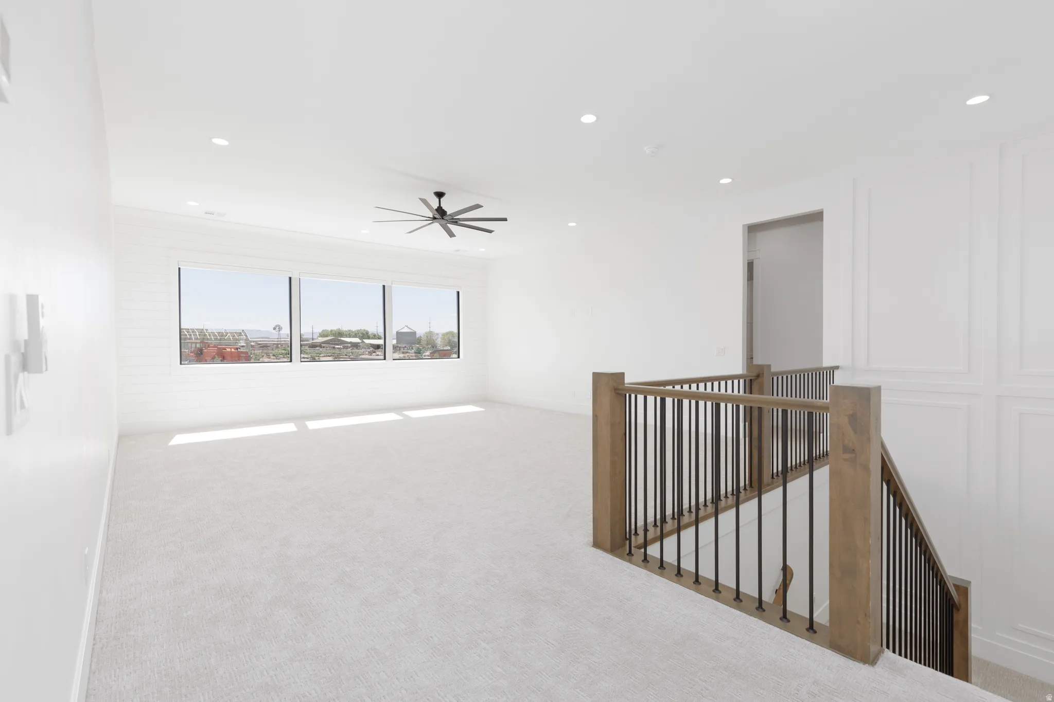 Expansive loft space with recessed lighting, large picture windows, and a ceiling fan