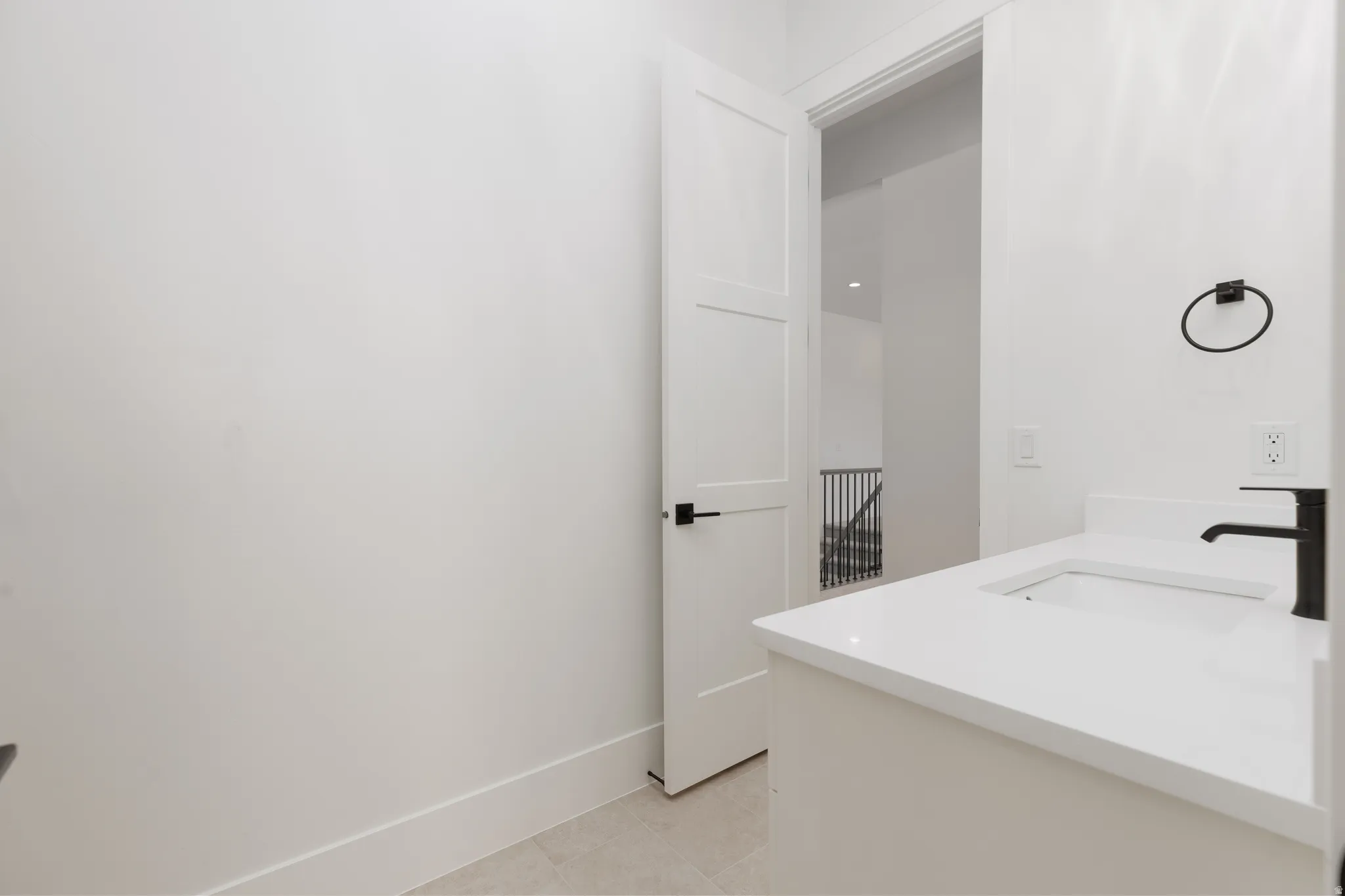 White vanity with an integrated sink, polished countertop, and matte black faucet