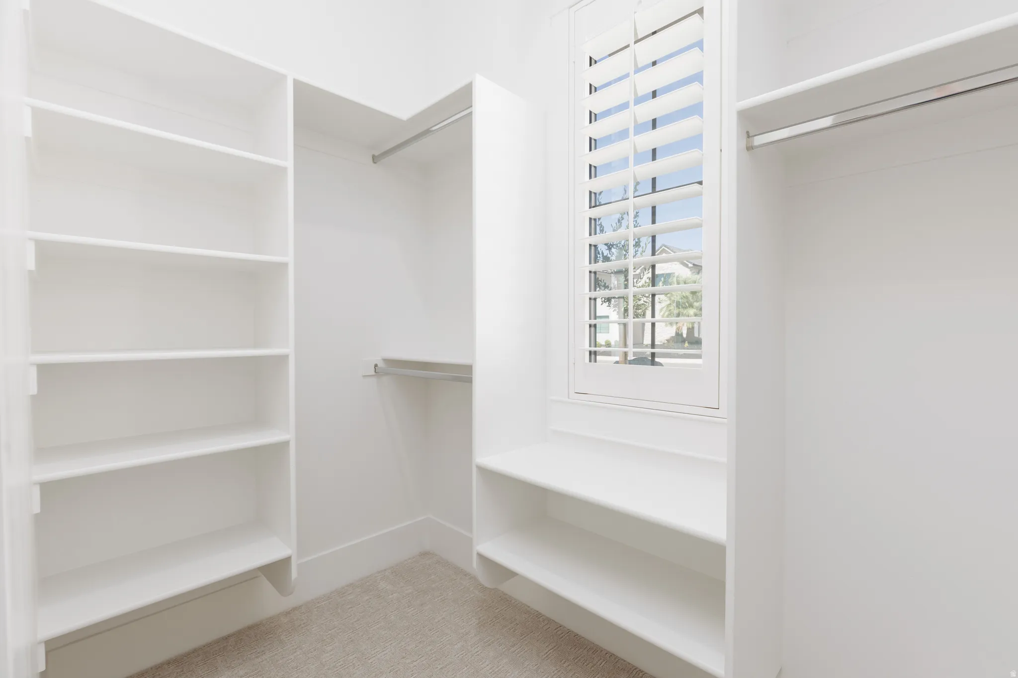 Walk-in closet featuring built-in shelving, hanging rods, and a window with plantation shutters