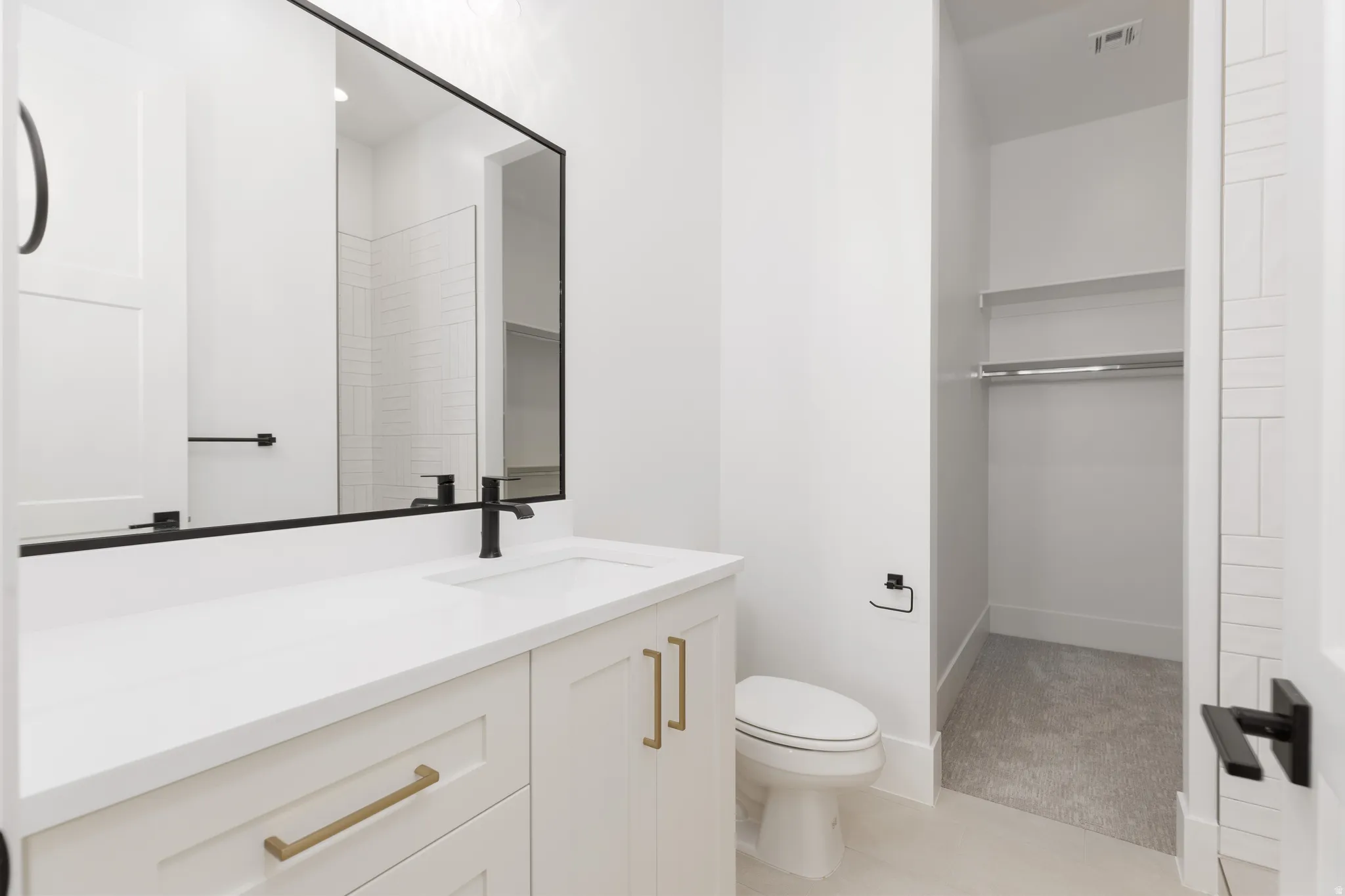 White vanity with brass hardware, undermount sink, and black faucet