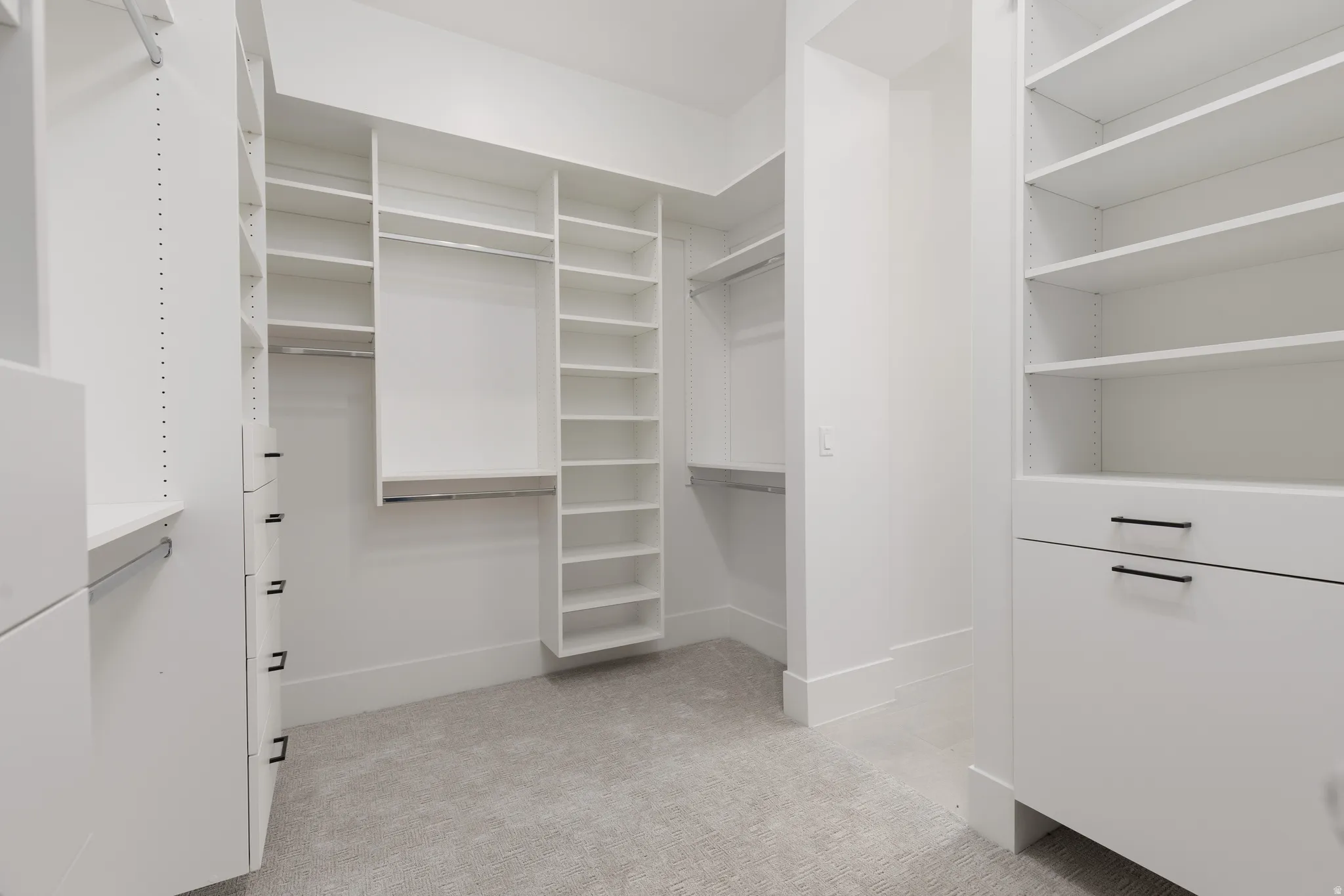 Custom closet system featuring multiple shelves, hanging rods, and built-in drawers with black hardware