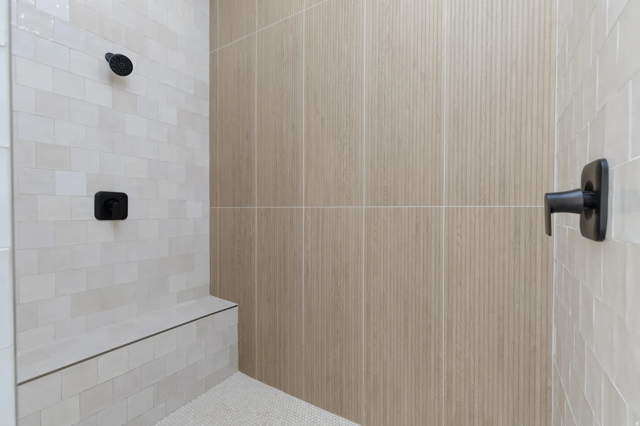 Walk-in shower with a built-in bench, matte black fixtures, and mixed tile finishes