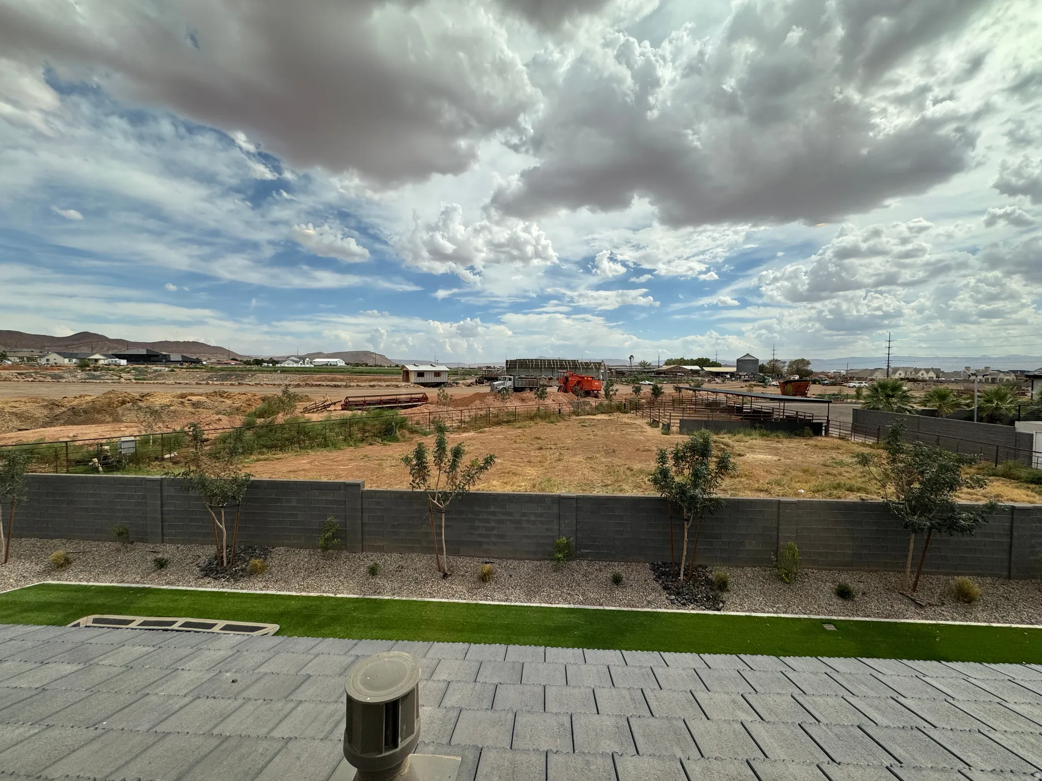 Expansive sky scape, paved patio, artificial turf, gravel landscaping, and block wall fencing