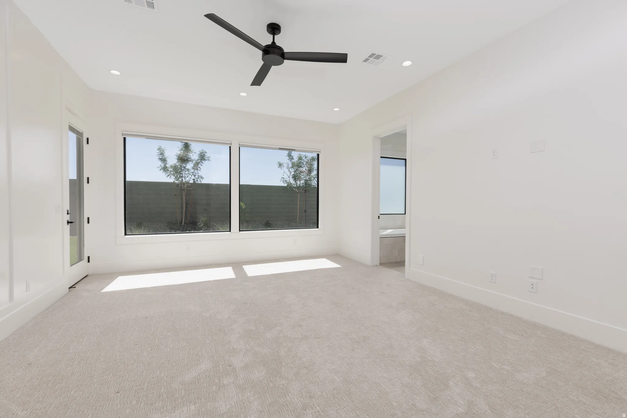 Light-toned carpet flooring, recessed ceiling lighting, and a modern ceiling fan