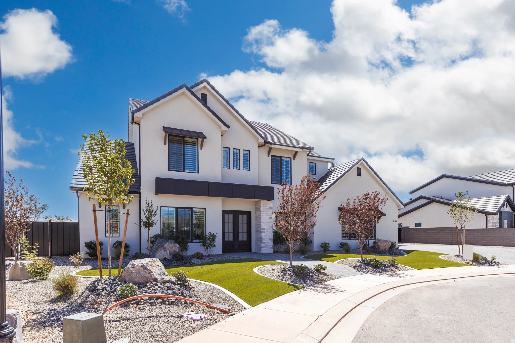 Contemporary stucco exterior with a stone accent facade, featuring a dark tile roof