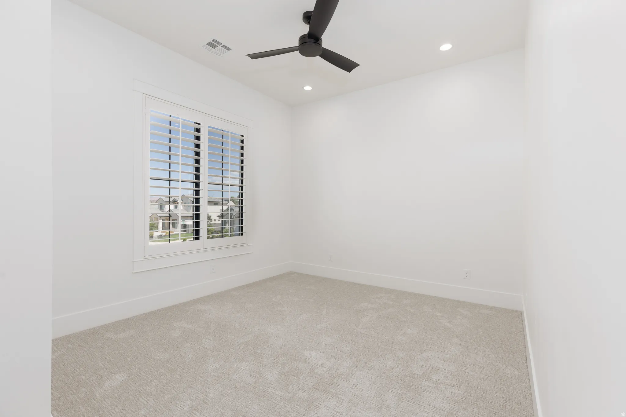 Window with plantation shutters, ceiling fan, recessed lighting, and carpet flooring