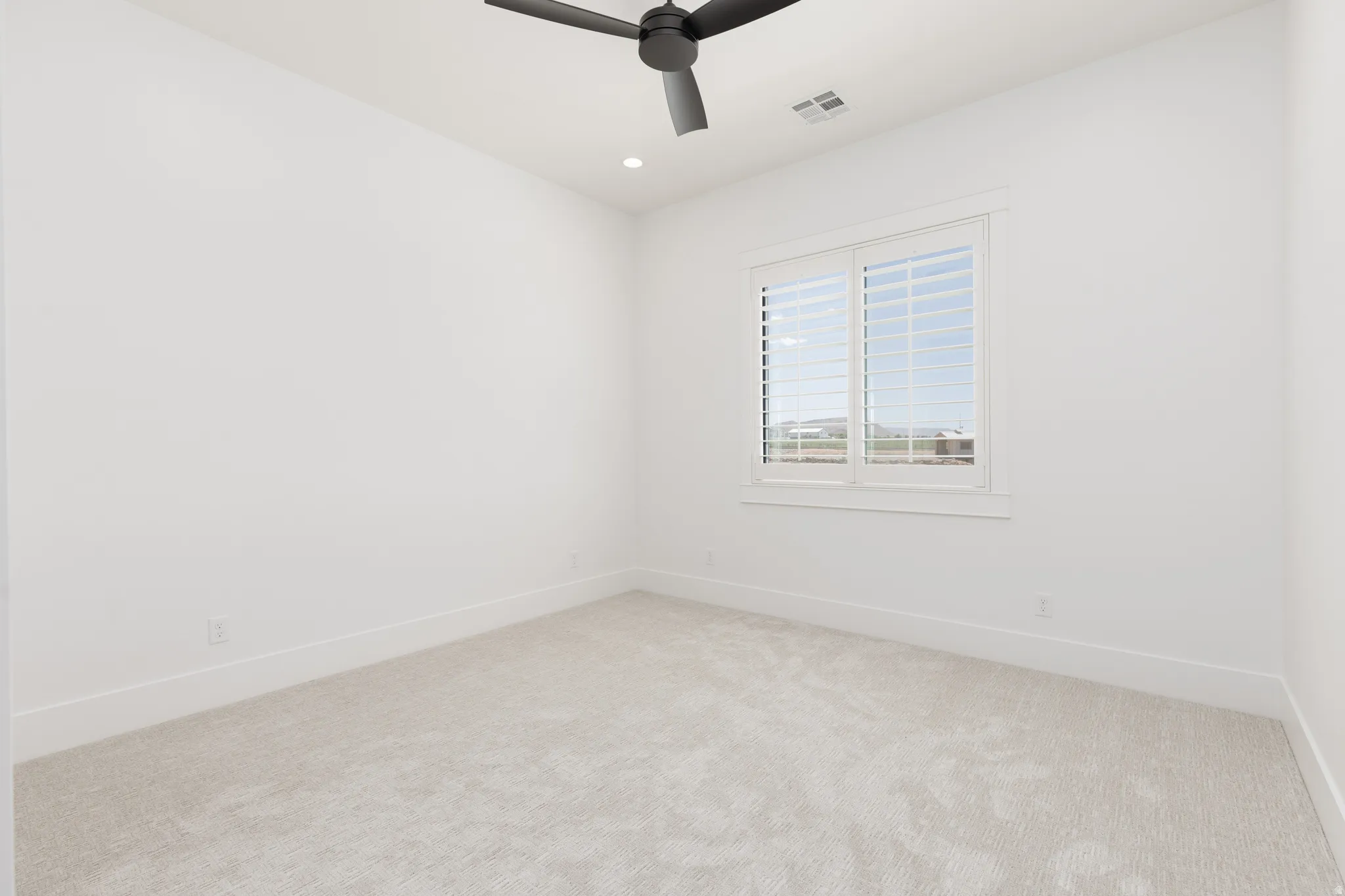Recessed lighting, ceiling fan, white window shutters, and light-toned carpeting