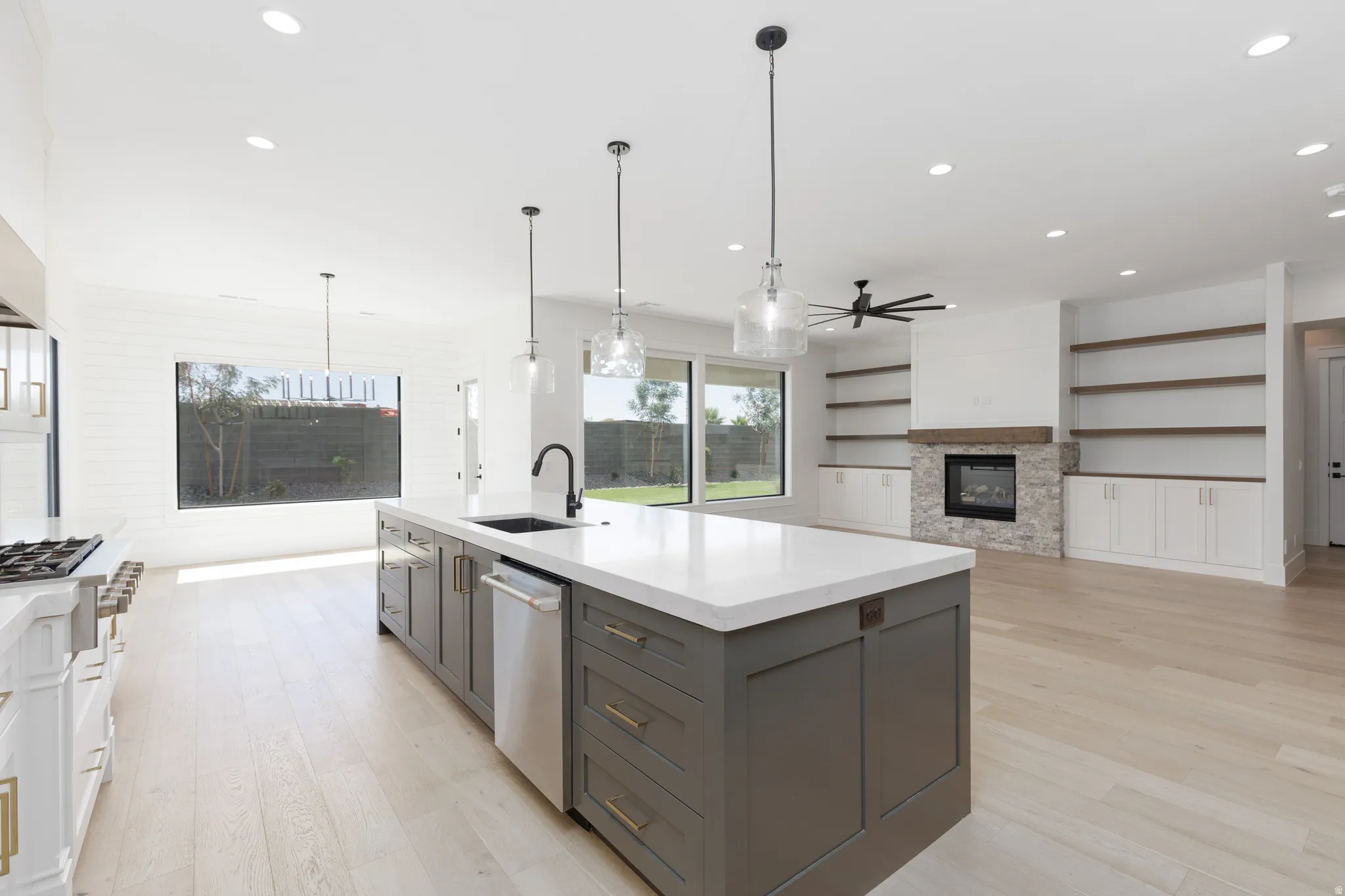 Spacious open-concept living area featuring a large kitchen island with integrated sink, recessed lighting, and light wood-finish flooring