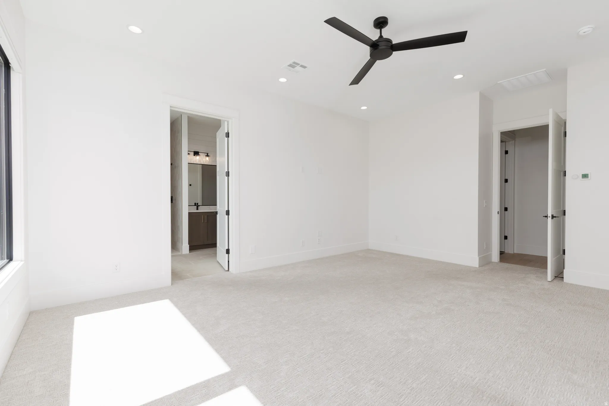Plush carpeting, recessed lighting, expansive window, and a modern ceiling fan