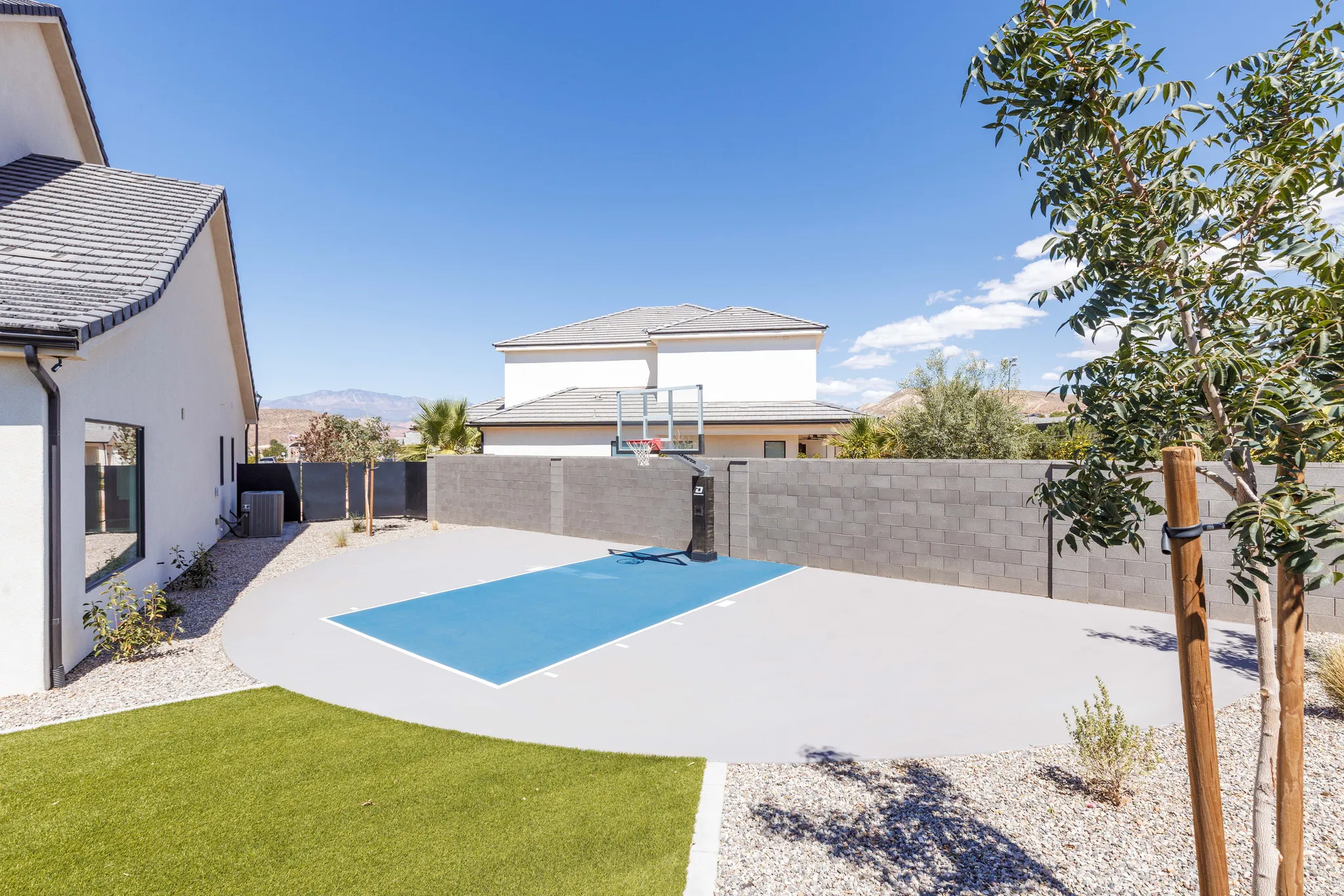 Expansive outdoor court with painted game lines, surrounded by a block wall and gravel landscaping