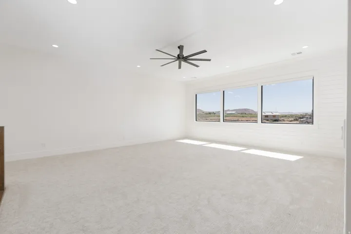 Spacious room featuring light-colored carpeting, recessed lighting, and a modern ceiling fan