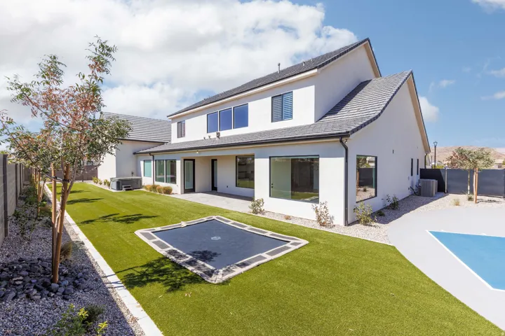 Expansive backyard featuring a manicured lawn, dedicated patio space, and mature trees