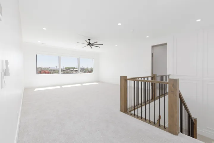 Expansive loft space with recessed lighting, large picture windows, and a ceiling fan