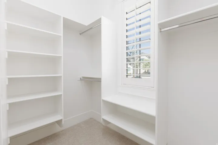 Walk-in closet featuring built-in shelving, hanging rods, and a window with plantation shutters