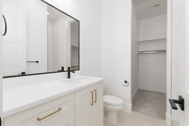 White vanity with brass hardware, undermount sink, and black faucet