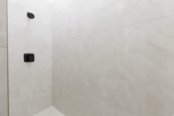 Shower enclosure with matte black fixtures and large format tiles