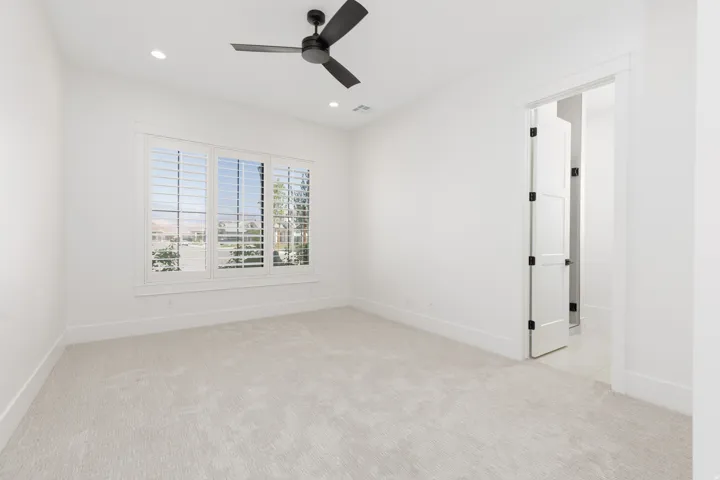 Recessed lighting, ceiling fan, and white plantation shutters complement the neutral wall finishes and plush carpeting