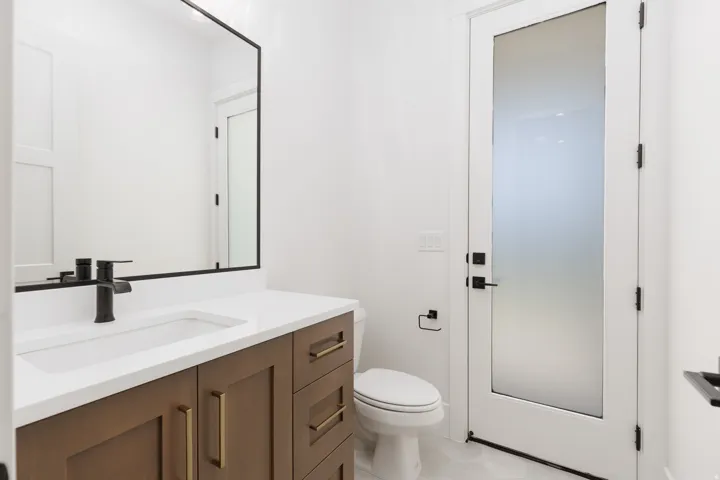 Floating vanity with wood-finish cabinetry, brass hardware, and a white countertop with an integrated sink