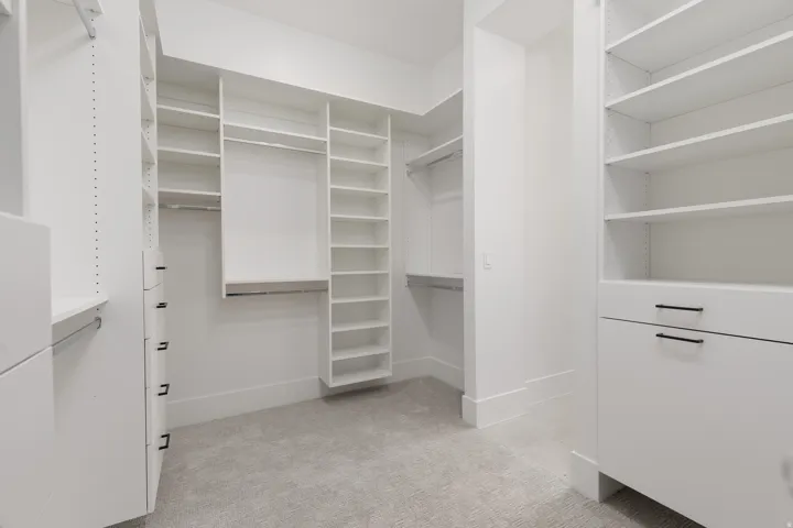 Custom closet system featuring multiple shelves, hanging rods, and built-in drawers with black hardware