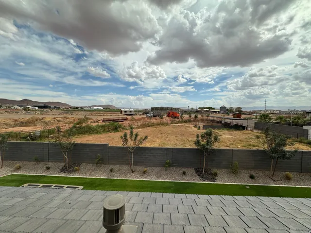 Expansive sky scape, paved patio, artificial turf, gravel landscaping, and block wall fencing