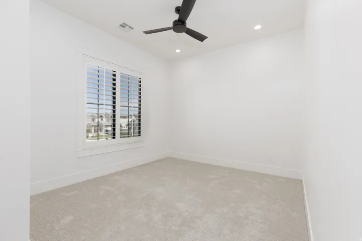 Window with plantation shutters, ceiling fan, recessed lighting, and carpet flooring