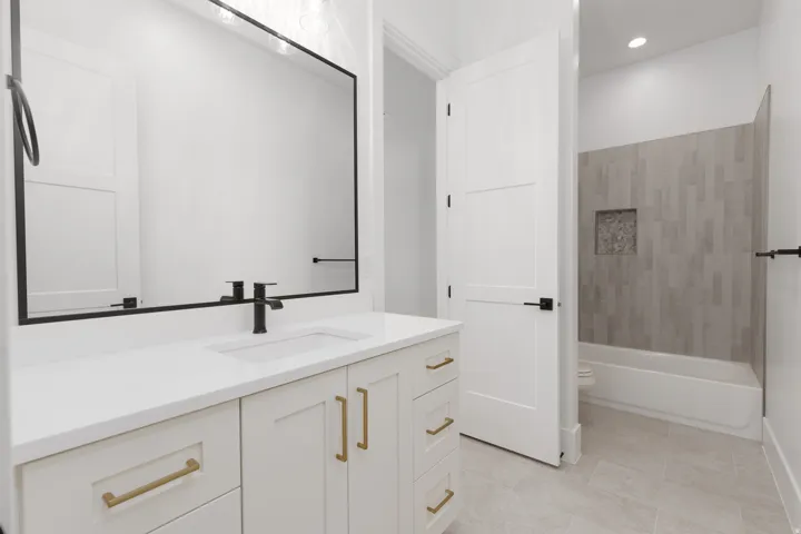 White vanity with gold-tone hardware, rectangular undermount sink, and black faucet
