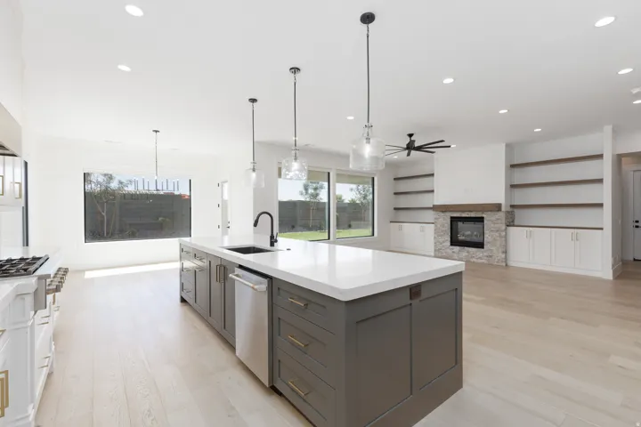 Spacious open-concept living area featuring a large kitchen island with integrated sink, recessed lighting, and light wood-finish flooring