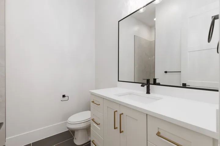 Single vanity with a white countertop and integrated sink, matte black faucet, and brass-finish hardware on cabinetry