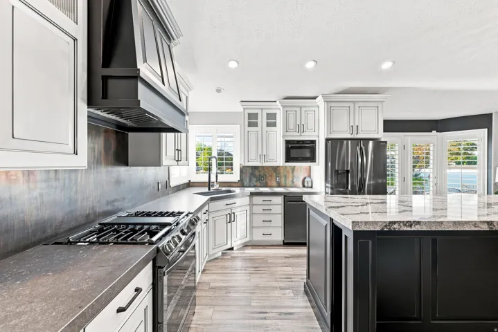 Gourmet kitchen featuring a gas range, built-in microwave, and black stainless steel refrigerator