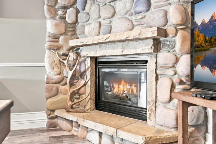 Stone fireplace surround with a gas insert, stone hearth, and mantel