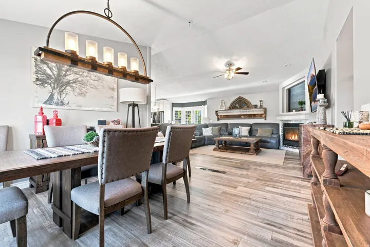 Vaulted ceilings, wood-finish flooring, a contemporary fireplace, and a ceiling fan create a comfortable living environment