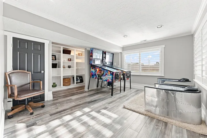 Recessed lighting, wood-finish flooring, built-in shelving, white plantation shutters, and a dark paneled door