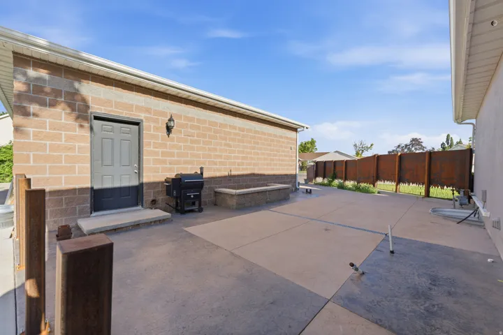 Expansive hardscaping with varied concrete finishes, gas fireplace and plumed for outside kitchen.