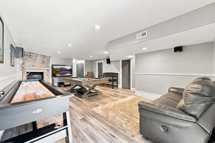 Stone-clad fireplace feature, recessed lighting, wood-finish flooring, wainscoting, and neutral wall tones