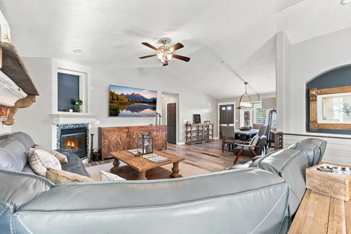 Vaulted ceiling, ceiling fan, fireplace with decorative tile surround, wood-finish flooring, and decorative nook.